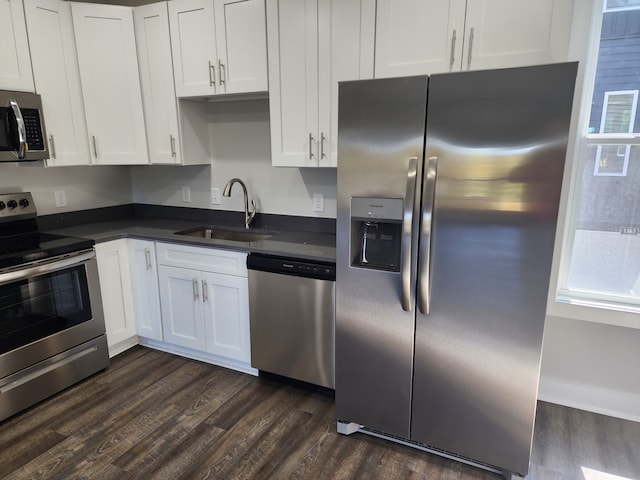 kitchen with appliances with stainless steel finishes, white cabinetry, sink, and dark wood-type flooring