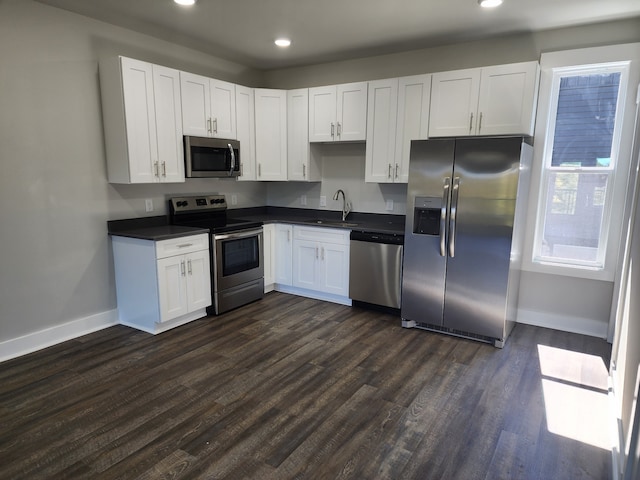 kitchen with dark wood-type flooring, stainless steel appliances, white cabinetry, and sink