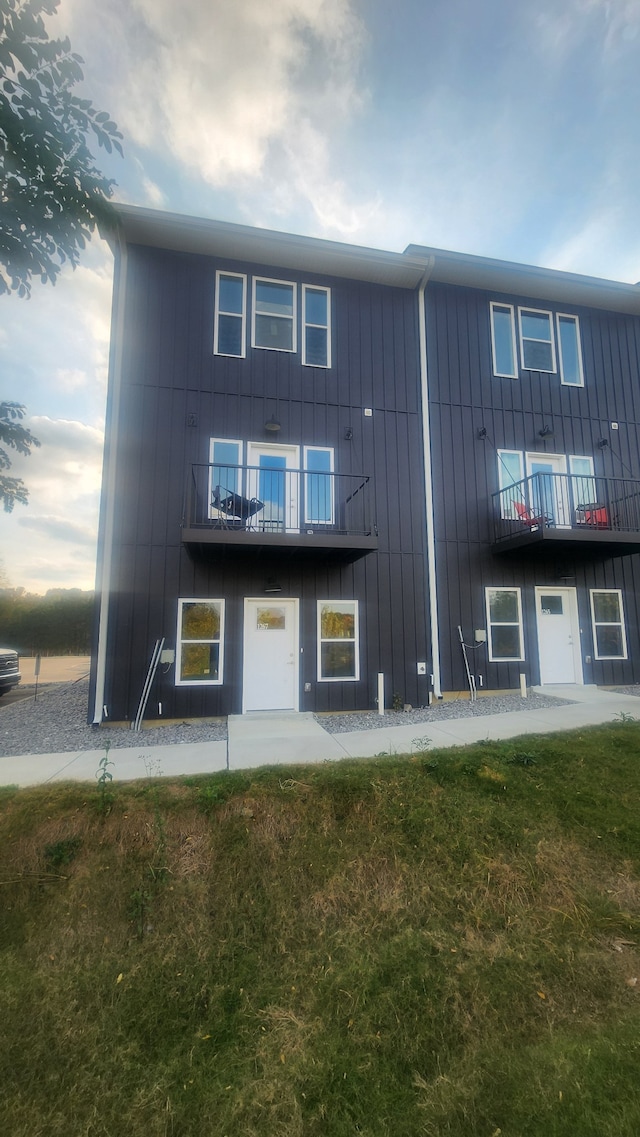 rear view of property with a lawn and a balcony