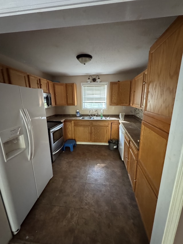 kitchen with dark tile patterned floors, stainless steel appliances, and sink