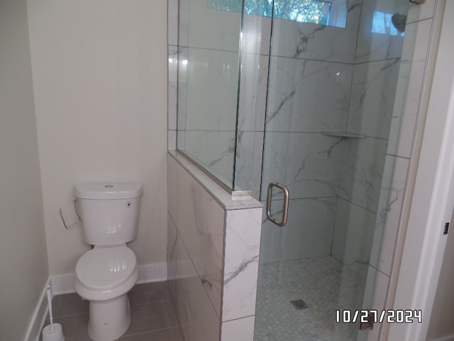 bathroom featuring toilet, a shower with shower door, and tile patterned flooring