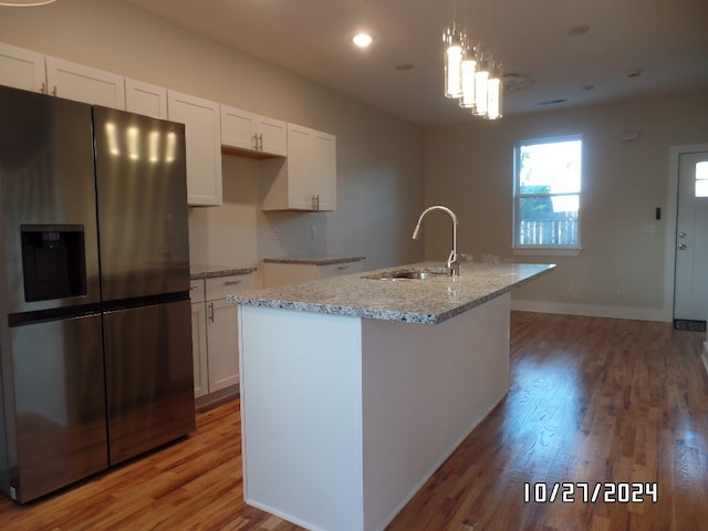 kitchen with a center island with sink, stainless steel fridge with ice dispenser, white cabinetry, and light hardwood / wood-style floors