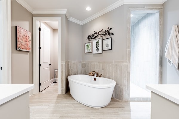 bathroom with ornamental molding, vanity, tile walls, and a bathing tub