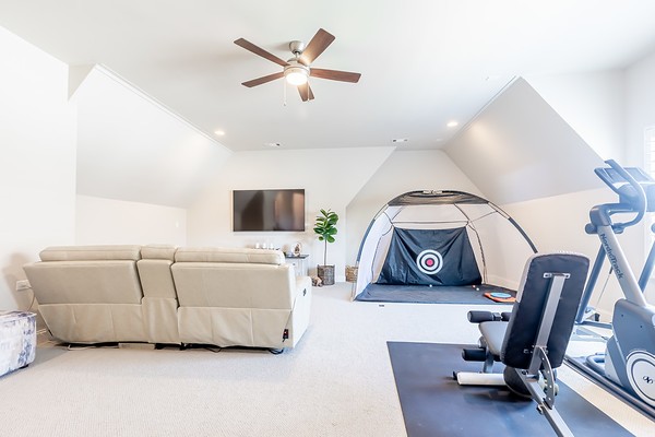 workout room with a wealth of natural light, ceiling fan, carpet floors, and vaulted ceiling