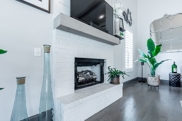 living room with a fireplace, a towering ceiling, and dark wood-type flooring