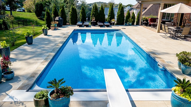 view of swimming pool with a diving board and a patio area