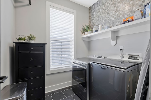 laundry area featuring washer and clothes dryer, dark tile patterned flooring, and plenty of natural light