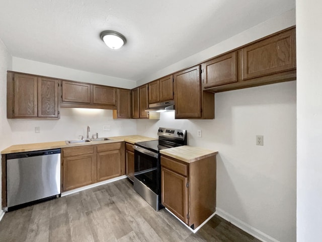 kitchen with butcher block counters, sink, appliances with stainless steel finishes, and light hardwood / wood-style flooring