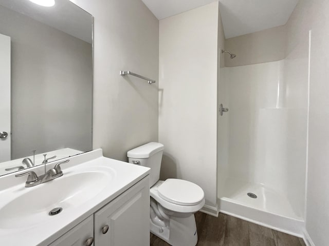 bathroom with walk in shower, hardwood / wood-style floors, vanity, and toilet