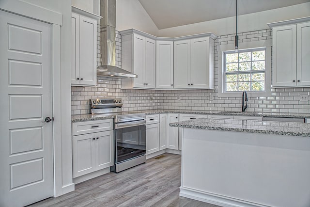 kitchen with wall chimney exhaust hood, light hardwood / wood-style flooring, stainless steel range with electric stovetop, sink, and white cabinetry