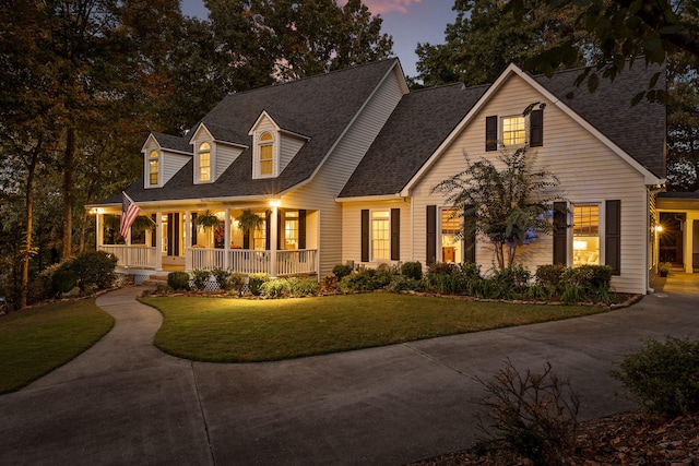 cape cod home with a lawn and a porch