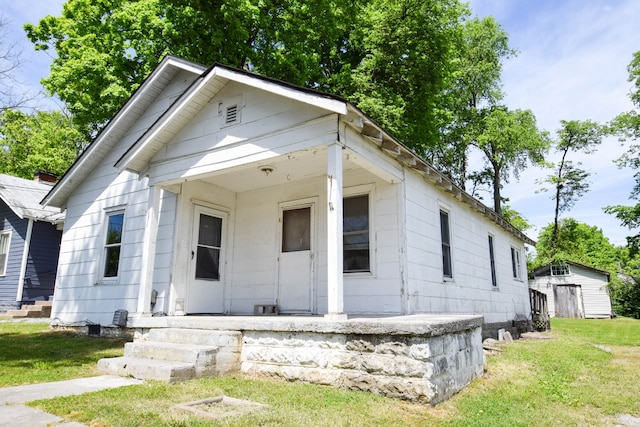 bungalow featuring a storage unit and a front yard