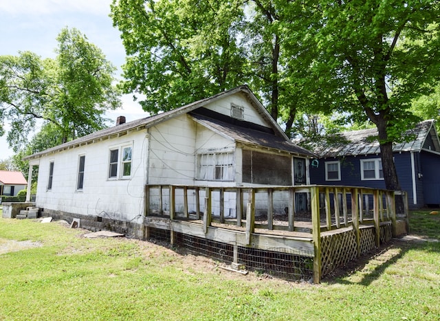 back of property featuring a deck, a sunroom, and a lawn