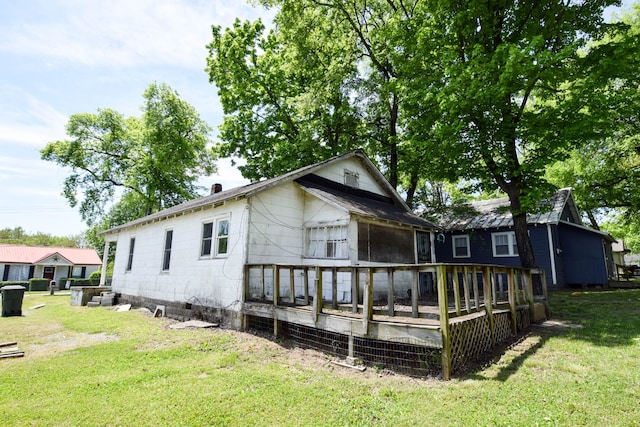 back of house with a wooden deck, a yard, and a sunroom