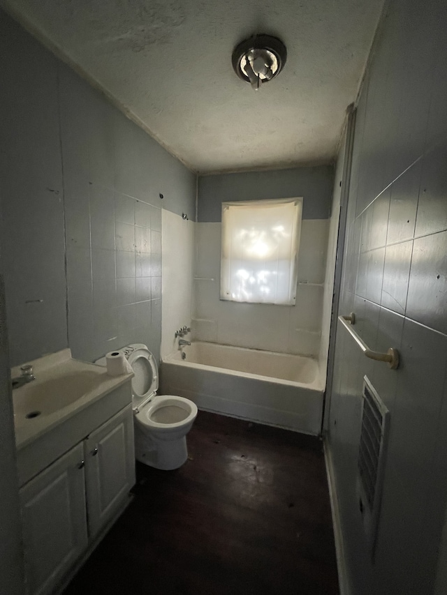 full bathroom with hardwood / wood-style flooring, toilet, vanity, tile walls, and washtub / shower combination