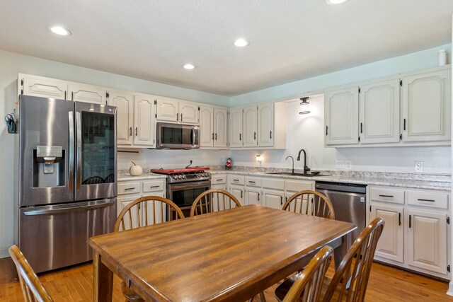 kitchen featuring light hardwood / wood-style floors, white cabinetry, sink, and appliances with stainless steel finishes