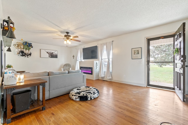 living room featuring light hardwood / wood-style floors, a textured ceiling, and a wealth of natural light