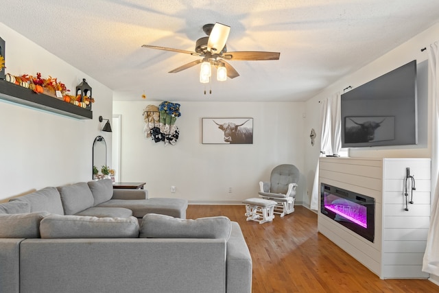 living room with hardwood / wood-style floors, ceiling fan, and a textured ceiling