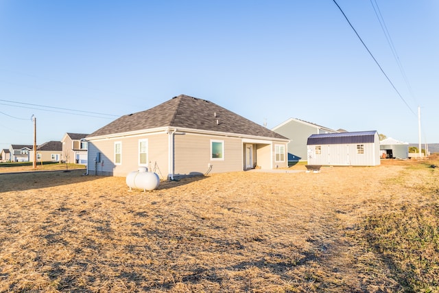 back of house with a storage shed