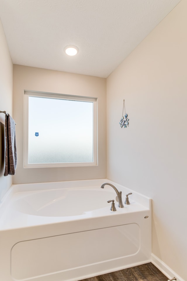 bathroom featuring a textured ceiling, wood-type flooring, and a washtub