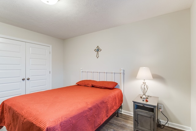 bedroom with a closet, a textured ceiling, and dark hardwood / wood-style flooring