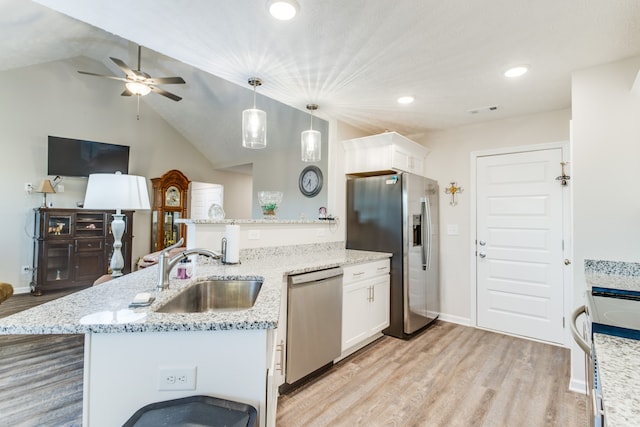 kitchen featuring lofted ceiling, hanging light fixtures, white cabinetry, sink, and stainless steel appliances