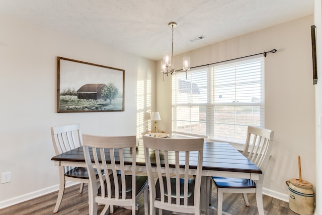 dining area featuring a textured ceiling, dark hardwood / wood-style flooring, and an inviting chandelier