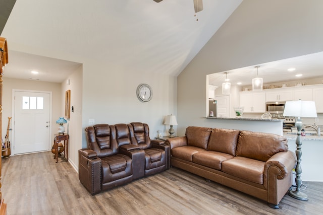 living room with high vaulted ceiling, light wood-type flooring, and ceiling fan