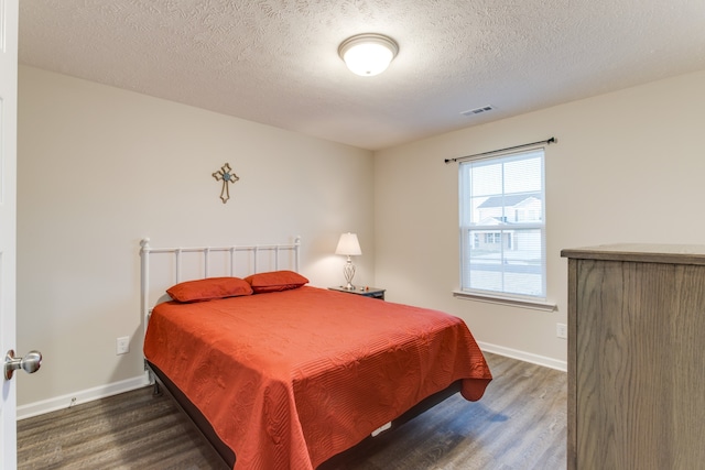 bedroom with dark wood-type flooring and a textured ceiling