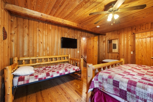 bedroom featuring hardwood / wood-style floors, wood ceiling, ceiling fan, and wood walls