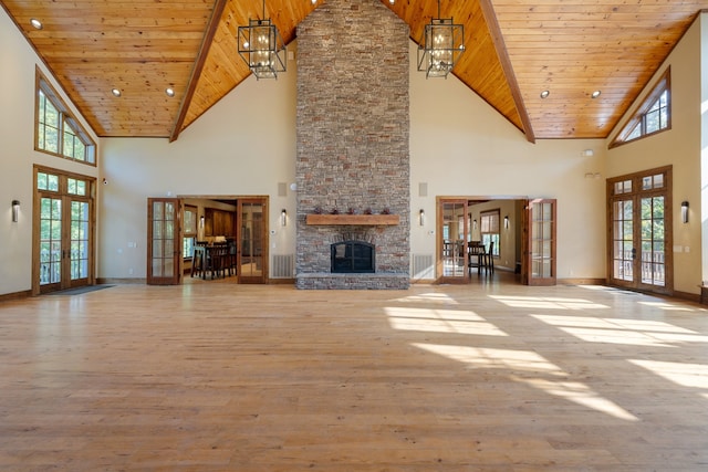 unfurnished living room featuring french doors, light wood-type flooring, high vaulted ceiling, wooden ceiling, and a fireplace