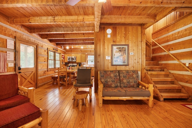 living room with light wood-type flooring, a healthy amount of sunlight, and wood walls