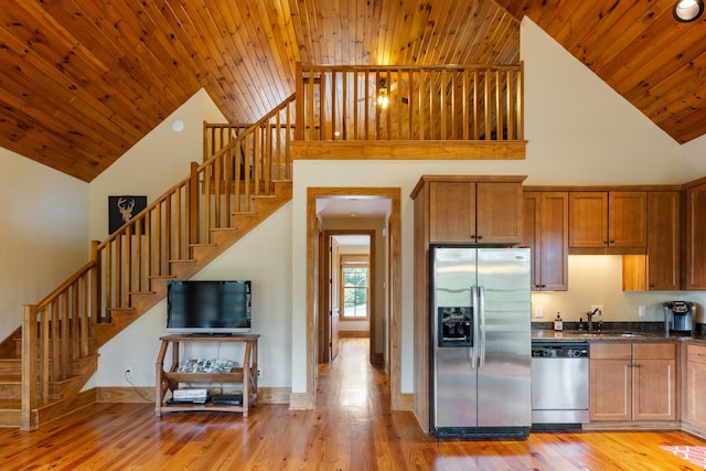 kitchen with appliances with stainless steel finishes, light hardwood / wood-style floors, high vaulted ceiling, and sink