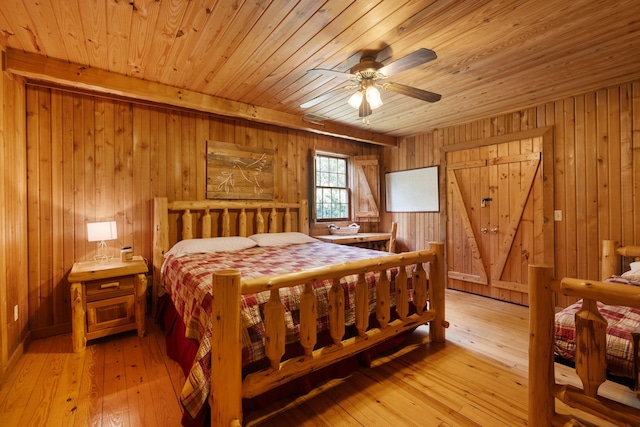 bedroom with light hardwood / wood-style flooring, ceiling fan, and wood walls