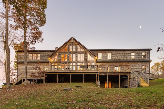 back house at dusk with a deck and a lawn