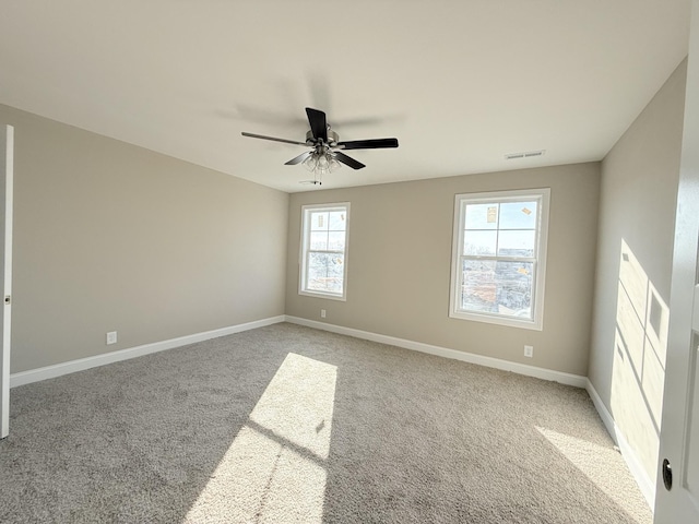 carpeted empty room featuring ceiling fan and a wealth of natural light