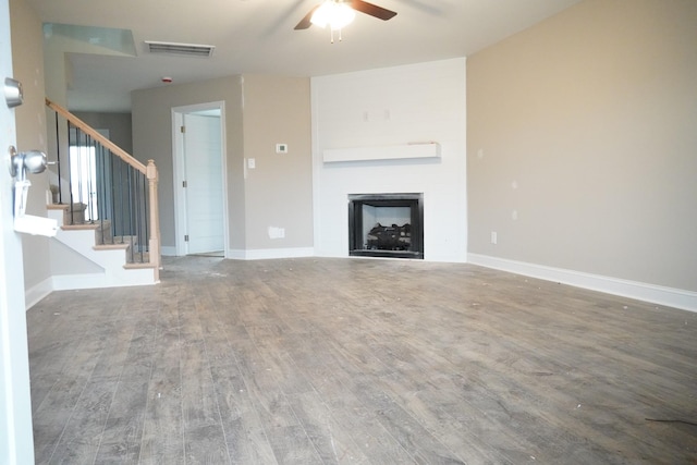 unfurnished living room with stairs, a fireplace, wood finished floors, and baseboards