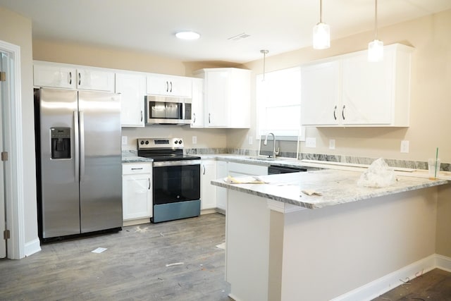 kitchen featuring stainless steel appliances, light stone counters, a peninsula, and a sink