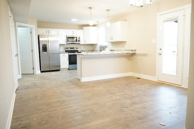 kitchen with light wood finished floors, baseboards, appliances with stainless steel finishes, a peninsula, and white cabinetry