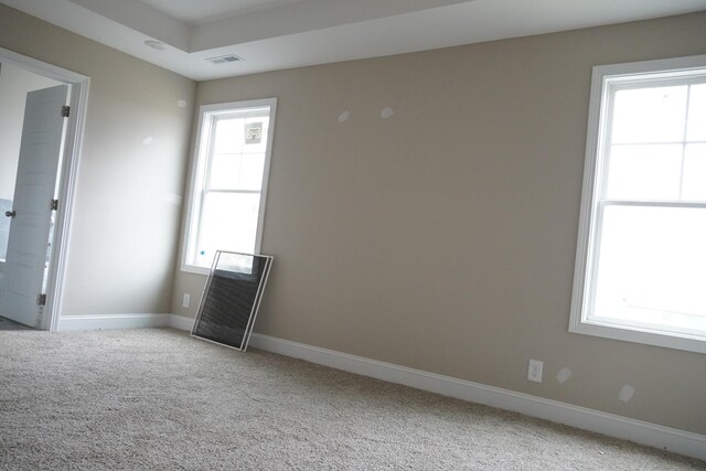 spare room with light carpet, plenty of natural light, visible vents, and baseboards