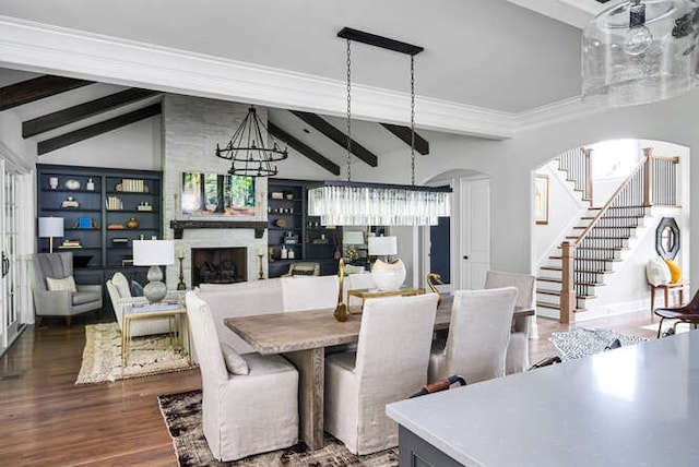 dining space featuring a large fireplace, lofted ceiling with beams, a chandelier, and dark hardwood / wood-style floors