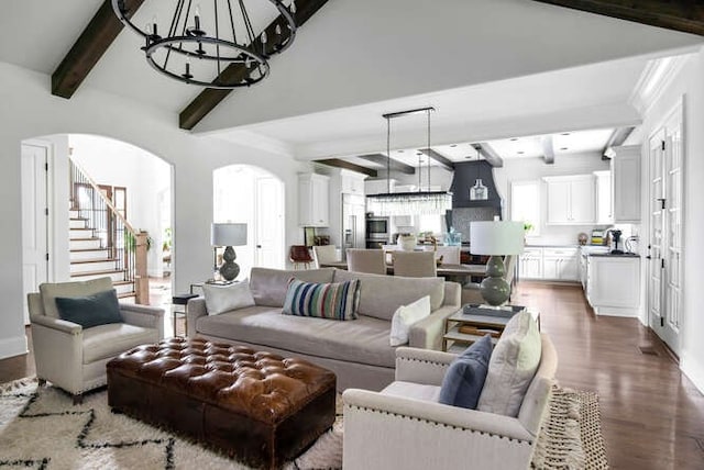 living room with a healthy amount of sunlight, hardwood / wood-style flooring, beamed ceiling, and an inviting chandelier