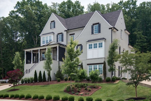 french provincial home featuring a front yard and a sunroom