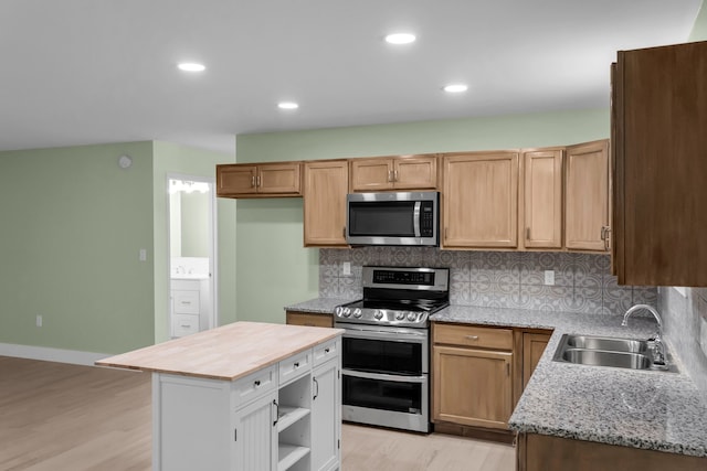 kitchen featuring wooden counters, tasteful backsplash, stainless steel appliances, sink, and a kitchen island