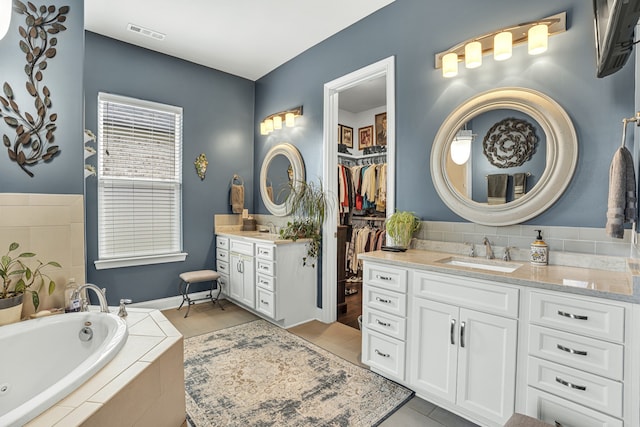 bathroom featuring tile patterned floors, vanity, and tiled tub