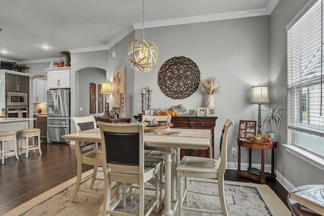 dining space with dark wood-type flooring, ornamental molding, and a notable chandelier