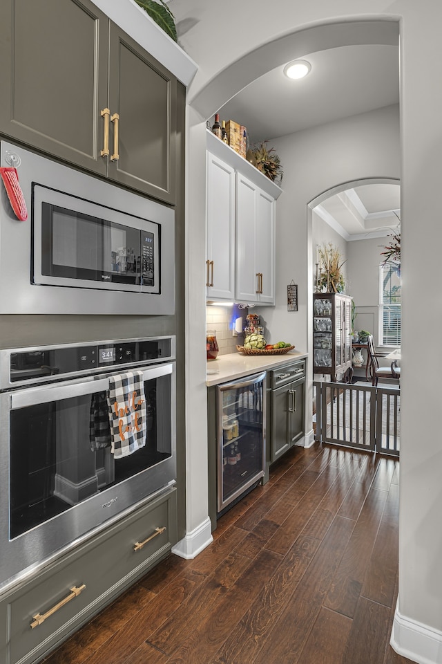 bar featuring appliances with stainless steel finishes, gray cabinetry, backsplash, wine cooler, and dark hardwood / wood-style flooring