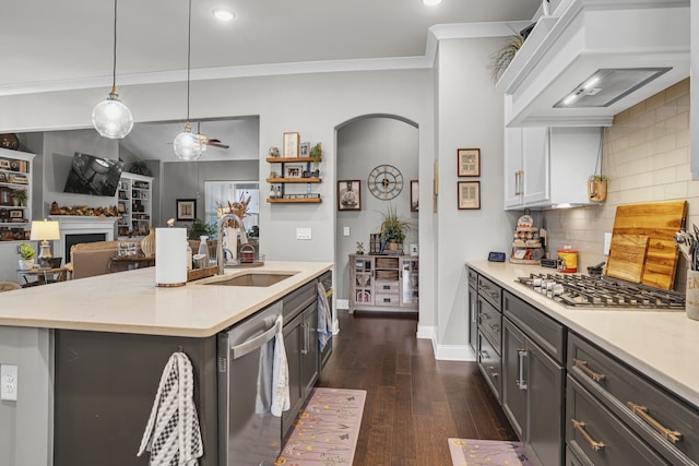 kitchen featuring sink, stainless steel appliances, tasteful backsplash, custom range hood, and decorative light fixtures