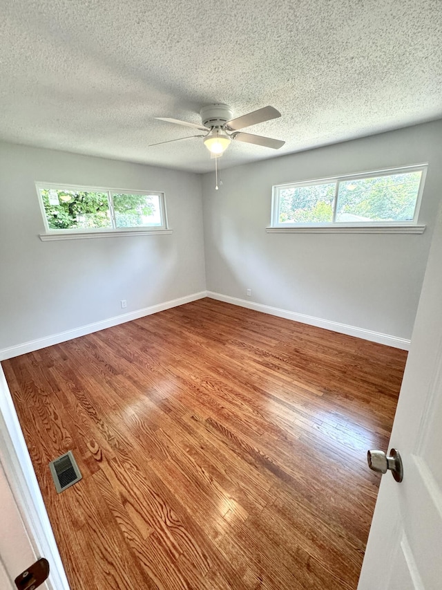 spare room with ceiling fan, wood-type flooring, a healthy amount of sunlight, and a textured ceiling