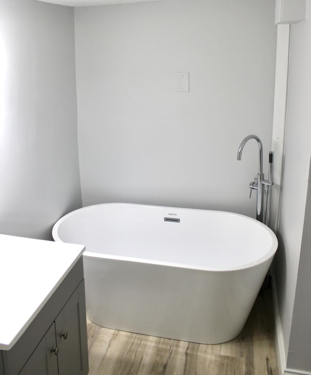 bathroom featuring vanity, hardwood / wood-style flooring, and a tub to relax in